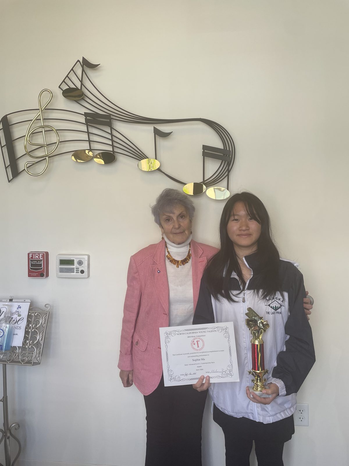 Dina Reznik with a student holding a certificate and trophy